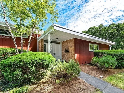 vintage MCM Fayetteville, NY house for sale with retro details, red wood exterior with flat roof and white front door