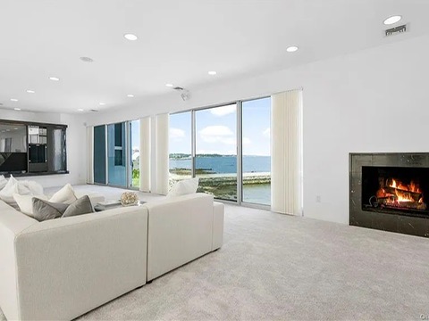 New Rochelle beach house in New York, living space overlooking the long island sound with massive glass doors and white carpet