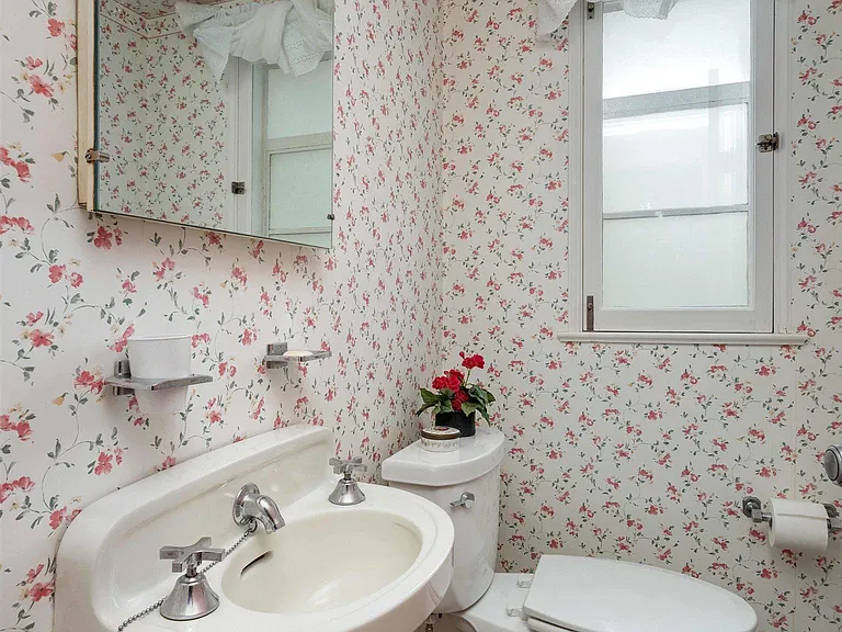 vintage Rock Island Illinois house, bathroom with vintage tilework and floral wallpaper with a white porcelain pedastal sink