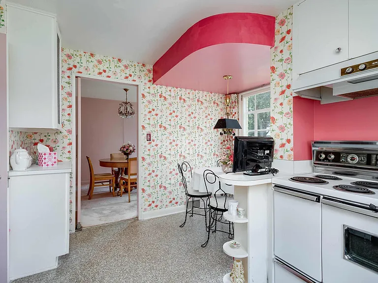 vintage Rock Island Illinois house, vintage floral wallpaper kitchen with retro pink formica detailing, floral accordian curtains and white cabinets