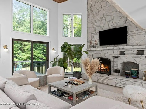 Woodstock NY retreat, soaring 25-foot ceilings finished with natural wood with modern neutral living room and stone fireplace