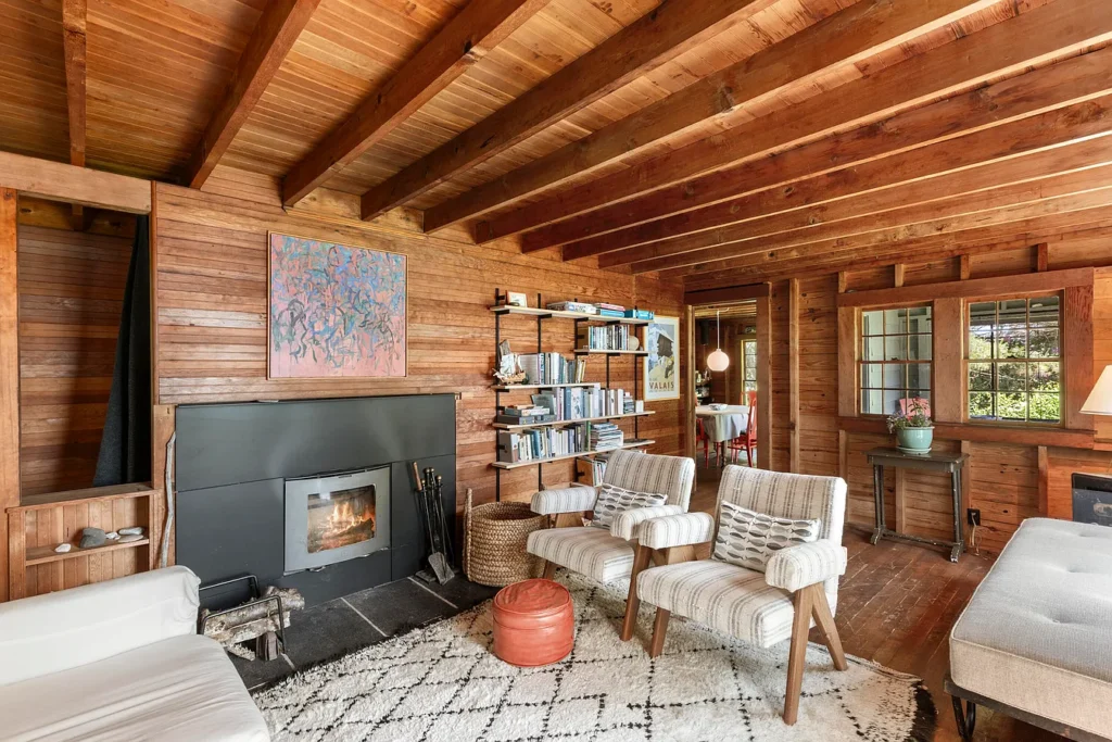 Rustic Maine Beach House, exposed natural wood beams living room with light furniture and fireplace