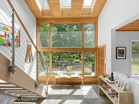 Woodstock NY retreat, soaring 25-foot ceilings finished with natural wood with modern neutral living room and stone fireplace