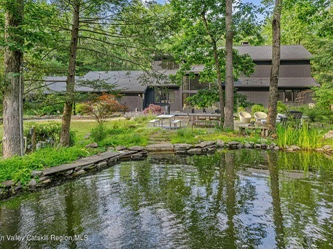 Woodstock NY retreat on 2.58 acres with landscaped exterior and black paint facing a large pond