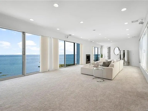 New Rochelle beach house in New York, living space overlooking the long island sound with massive glass doors and white carpet