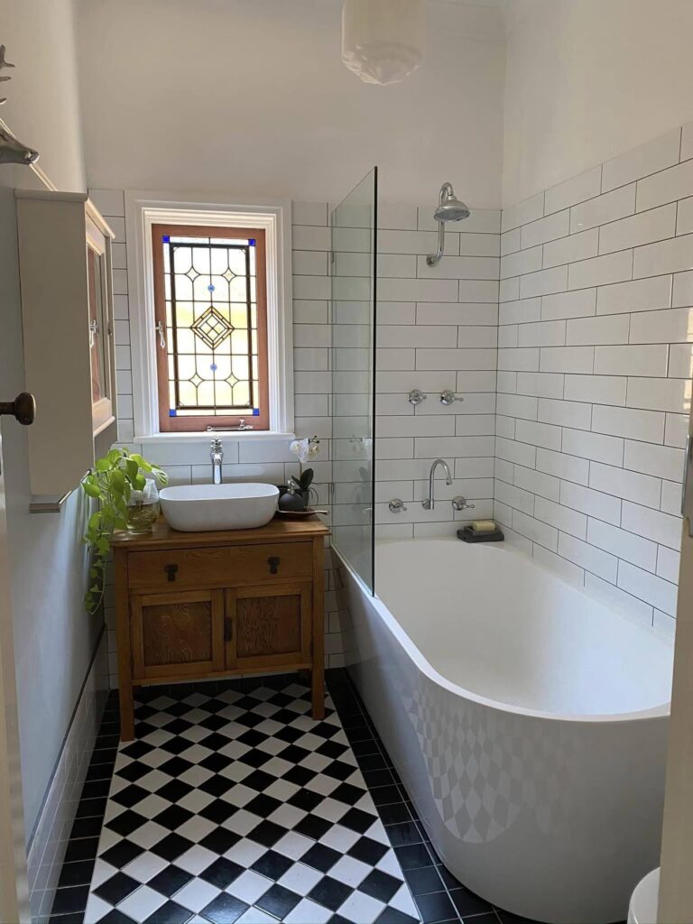 light bright rooms, bathroom with vintage windows, green plants and penny tile around a soaking tub