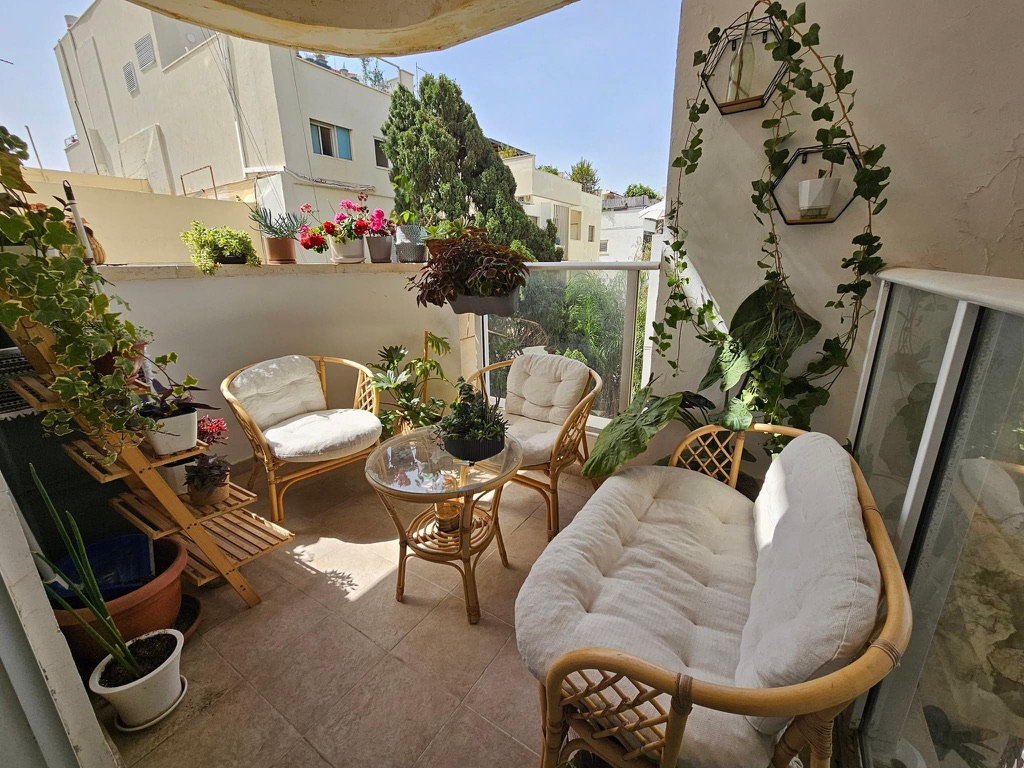 light bright rooms, tel aviv apartment with beige balcony furniture and green houseplants and lots of natural light