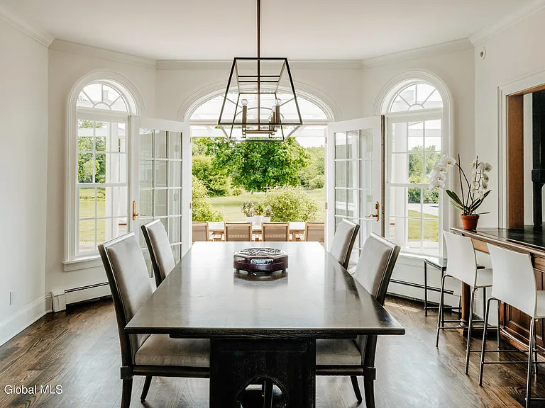 Valatie NY Equestrian Estate, modern industrial dining room with black dining room table and green velvet chairs with large chandelier