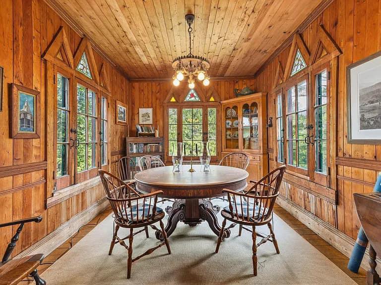 Keene Valley NY house with wood walls and ceilings and log cabin exterior well lit sun room with dining space