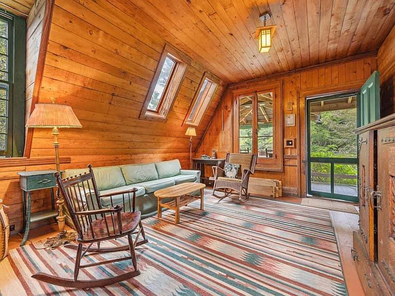 Keene Valley NY house with wood walls and ceilings and log cabin exterior with bright den and rocking chair