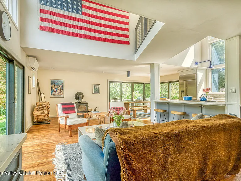 shandaken ny estate set on 35 private acres overlooking the catskill mountains, large modern kitchen open floor plan into living room with vaulted ceilings and american flag art