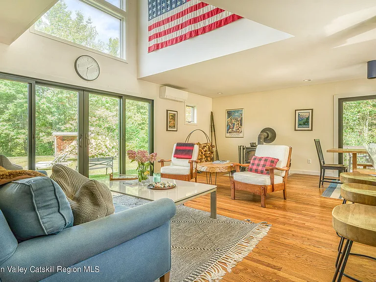 shandaken ny estate set on 35 private acres overlooking the catskill mountains, large modern kitchen open floor plan into living room with vaulted ceilings and american flag art