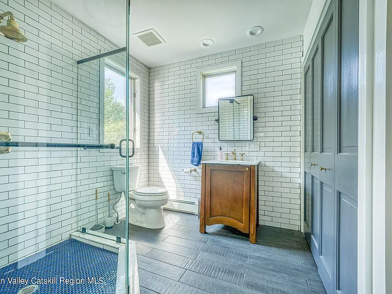 shandaken ny estate set on 35 private acres overlooking the catskill mountains, large full bathroom with blue floor tile and glass enclosed shower