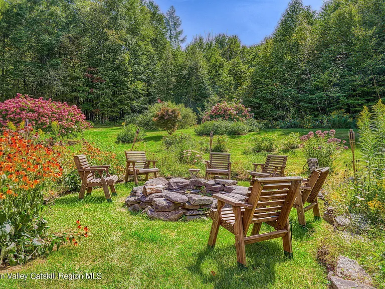 shandaken ny estate set on 35 private acres overlooking the catskill mountains, lush catskills forest surroundings with stone fire pit and adirondack chairs