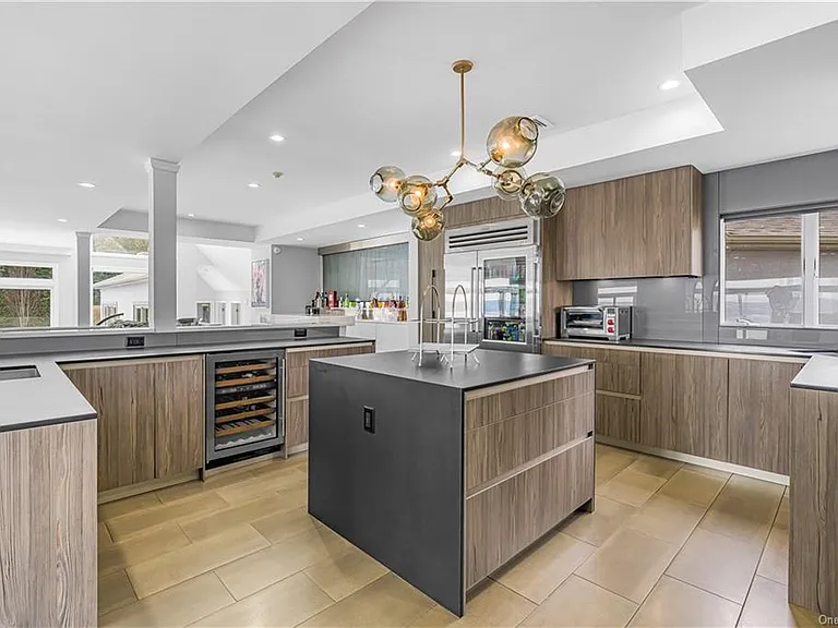 Modern Nyack, NY Palace with windows overlooking the hudson river, sleek kitchen with modern architectural chandelier and brown cabinets