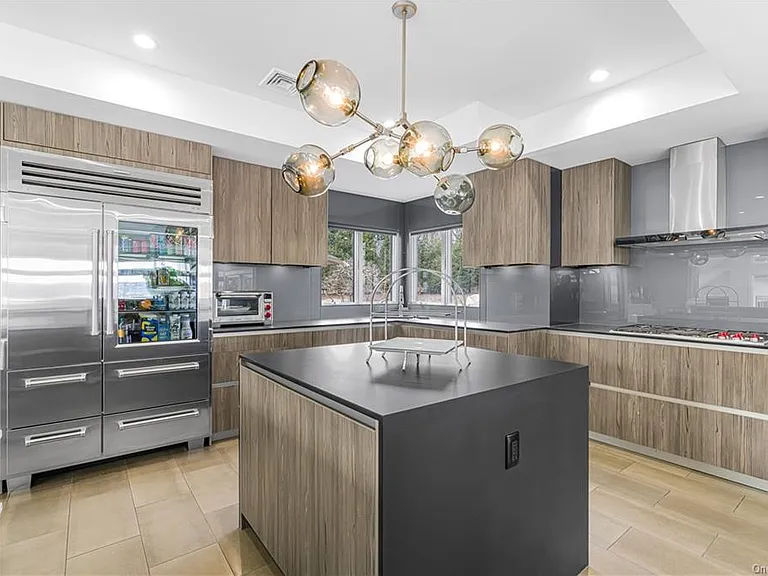 Modern Nyack, NY Palace with windows overlooking the hudson river, sleek kitchen with modern architectural chandelier and brown cabinets