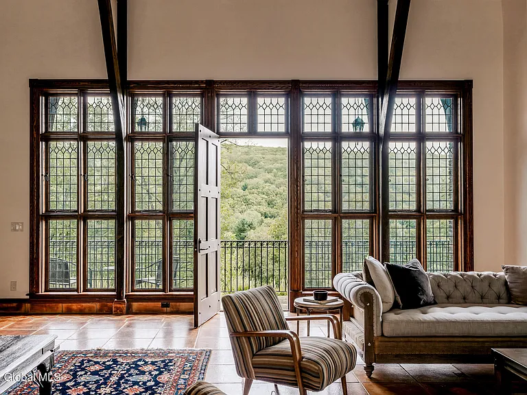 massive catskills ny castle for sale in sullivan county, light tudor style interior with tufted leather sofa and natural dark wood ceiling beams