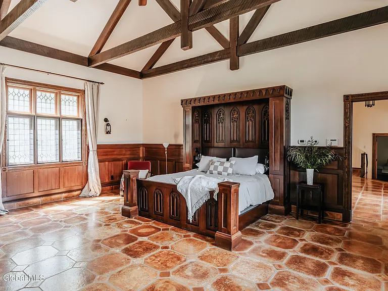 massive catskills ny castle for sale in sullivan county, tudor style master bedroom with vaulted ceilings and dark wood beams and a hand carved wood bedframe