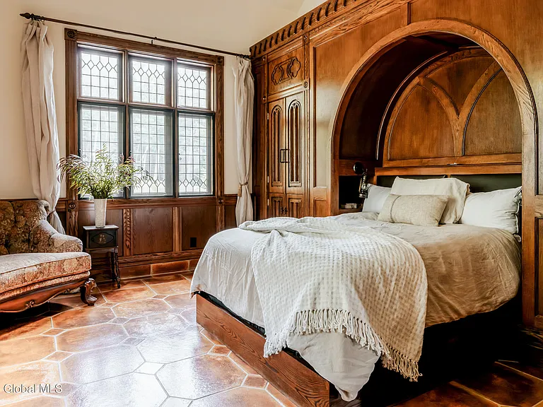 massive catskills ny castle for sale in sullivan county, tudor style master bedroom with vaulted ceilings and dark wood beams and a hand carved wood bedframe