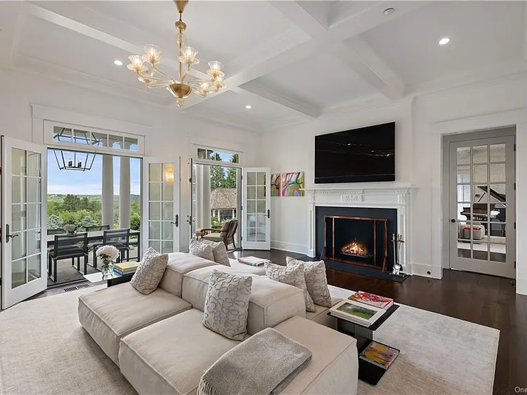 Westchester Mansion, interior of Happy Hill Farms in Bedford Corners New York with massive white double-sided sofa and tray ceilings with working gas fireplace