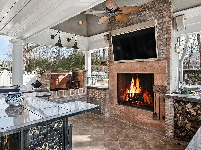 maximalist NJ mansion, 12 The Esplanade in Alpine New Jersey exterior patio with gas fireplace and outdoor kitchen