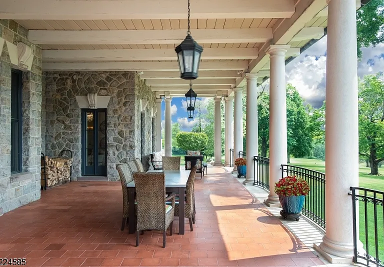 19th-Century Castle in New Jersey, exterior of a massive stone castle in Bernardsville NJ a gorgeous stone outdoor seating area overlooking the pool