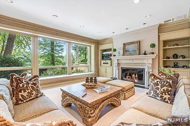 interior of a posh modern saddle river mansion in New Jersey's Bergen County, large room with wood burning fireplace and beige finishes