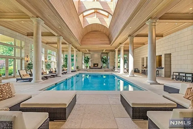 interior of a posh modern saddle river mansion in New Jersey's Bergen County, massive indoor pool with working fireplace