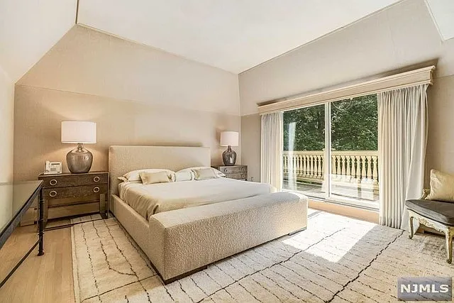 interior of a posh modern saddle river mansion in New Jersey's Bergen County, large master bedroom with wood burning fireplace and beige decor