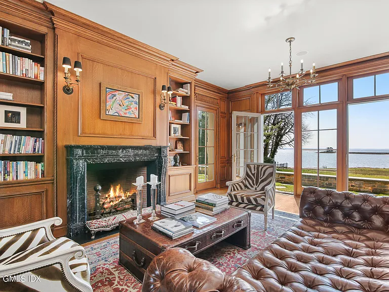 Massive Long Island Sound Mansion, interior of Cedarcliff Road in Riverside Connecticut with rich wood paneled den and wood burning fireplace