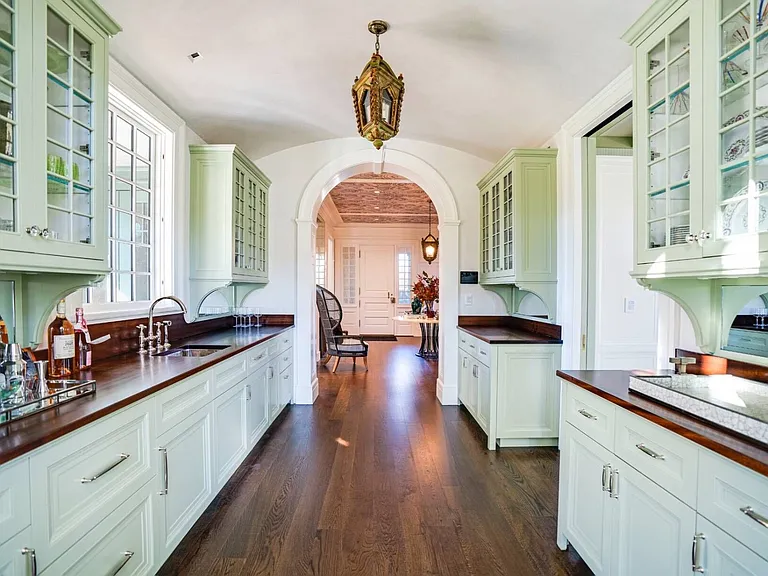 Old money Hamptons estate 134 Herrick Rd in Southampton New York, modern country style kitchen with green island and wood beams