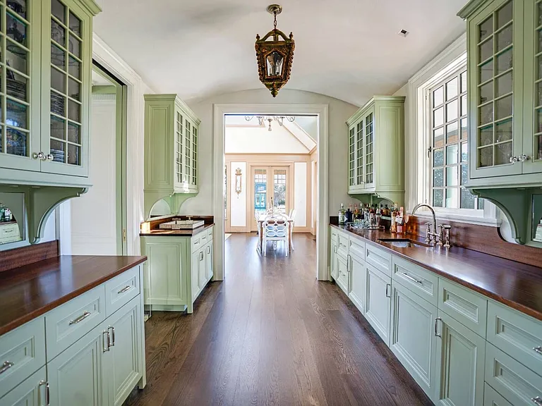 Old money Hamptons estate 134 Herrick Rd in Southampton New York, modern country style kitchen with green island and wood beams