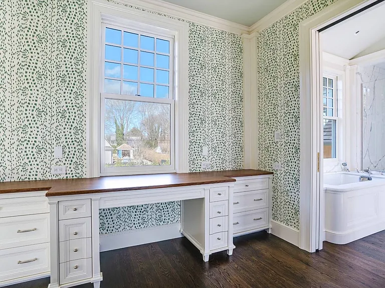 Old money Hamptons estate 134 Herrick Rd in Southampton New York, master bedroom with green patterned wallpaper and built-in home office desk