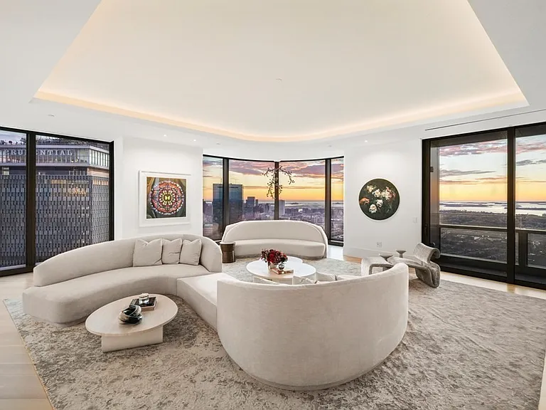 Boston's Most Expensive Penthouse Apartment, curved glass windows and round sofas overlooking the city of Boston from the 58th floor