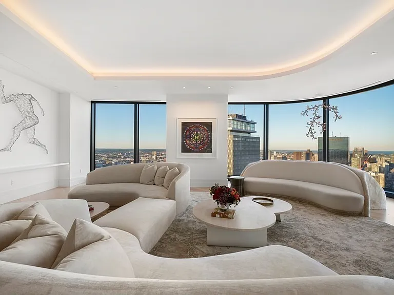 Boston's Most Expensive Penthouse Apartment, curved glass windows and round sofas overlooking the city of Boston from the 58th floor