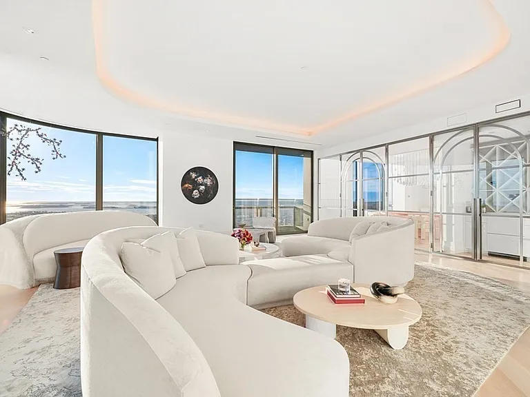 Boston's Most Expensive Penthouse Apartment, curved glass windows and round sofas overlooking the city of Boston from the 58th floor